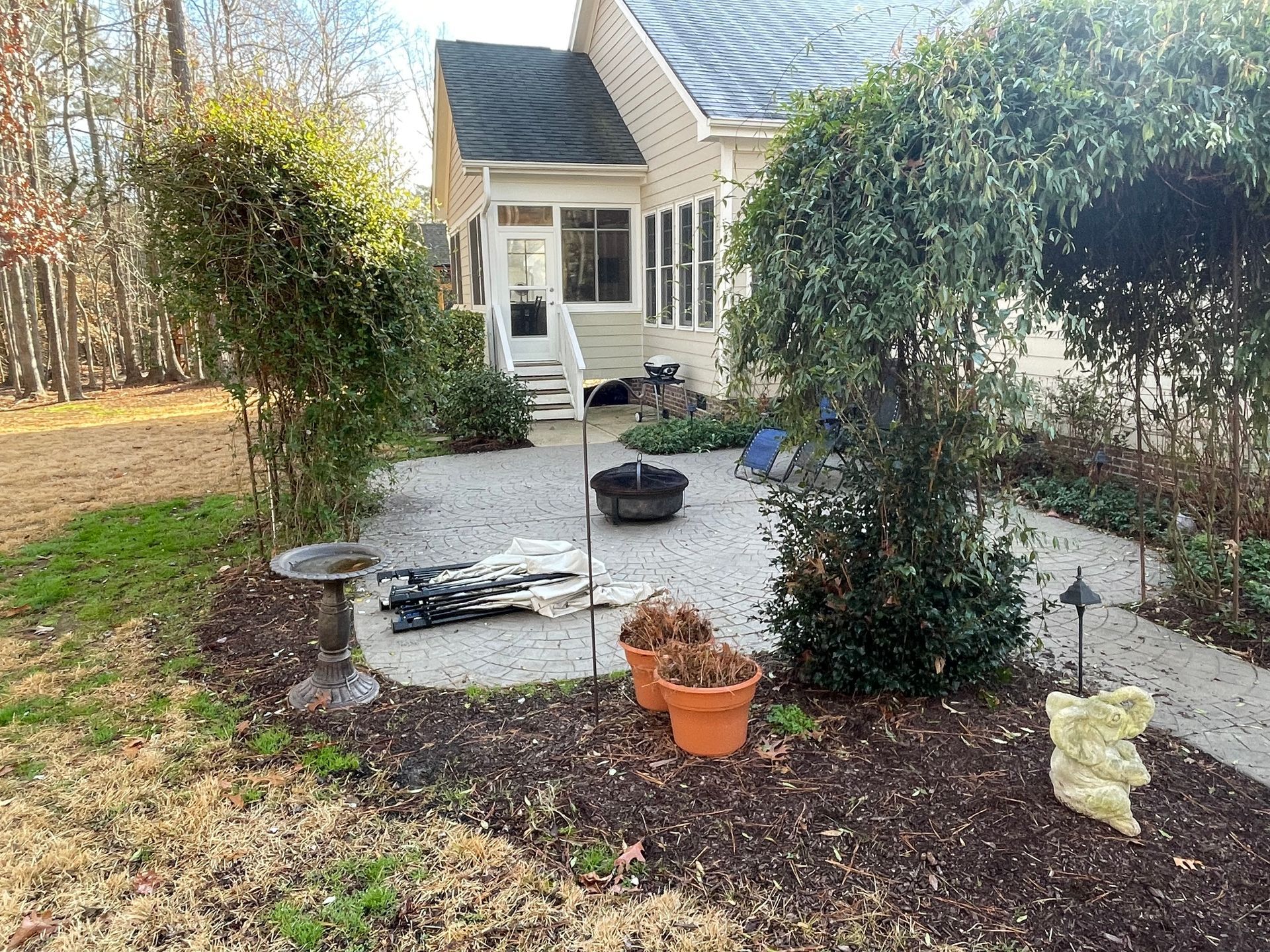 A house with a patio and potted plants in front of it.