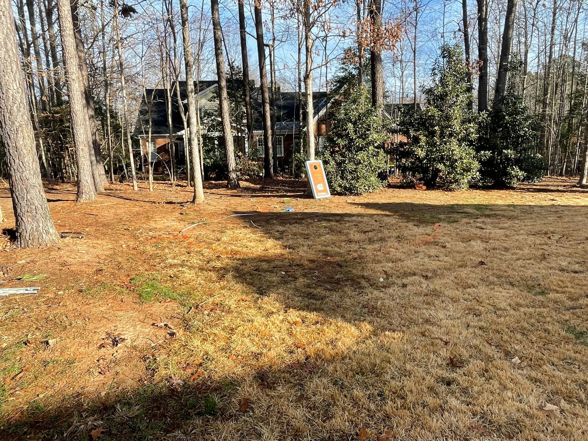 A large yard with a house in the background and trees in the background.