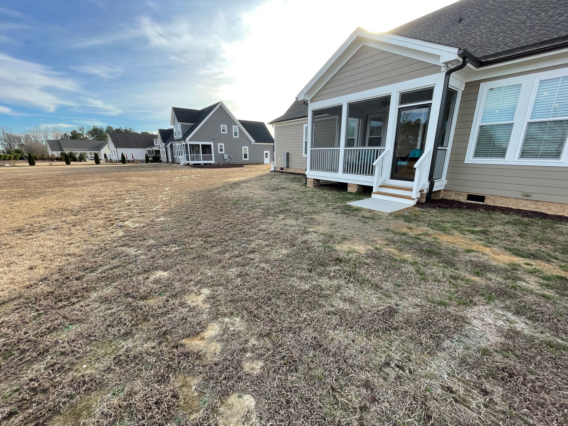 A house with a screened in porch and a lawn in front of it.