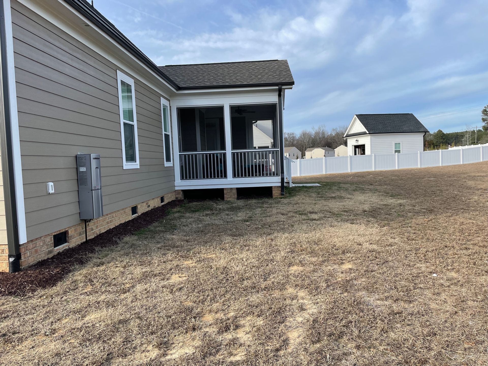 The backyard of a house with a screened in porch.