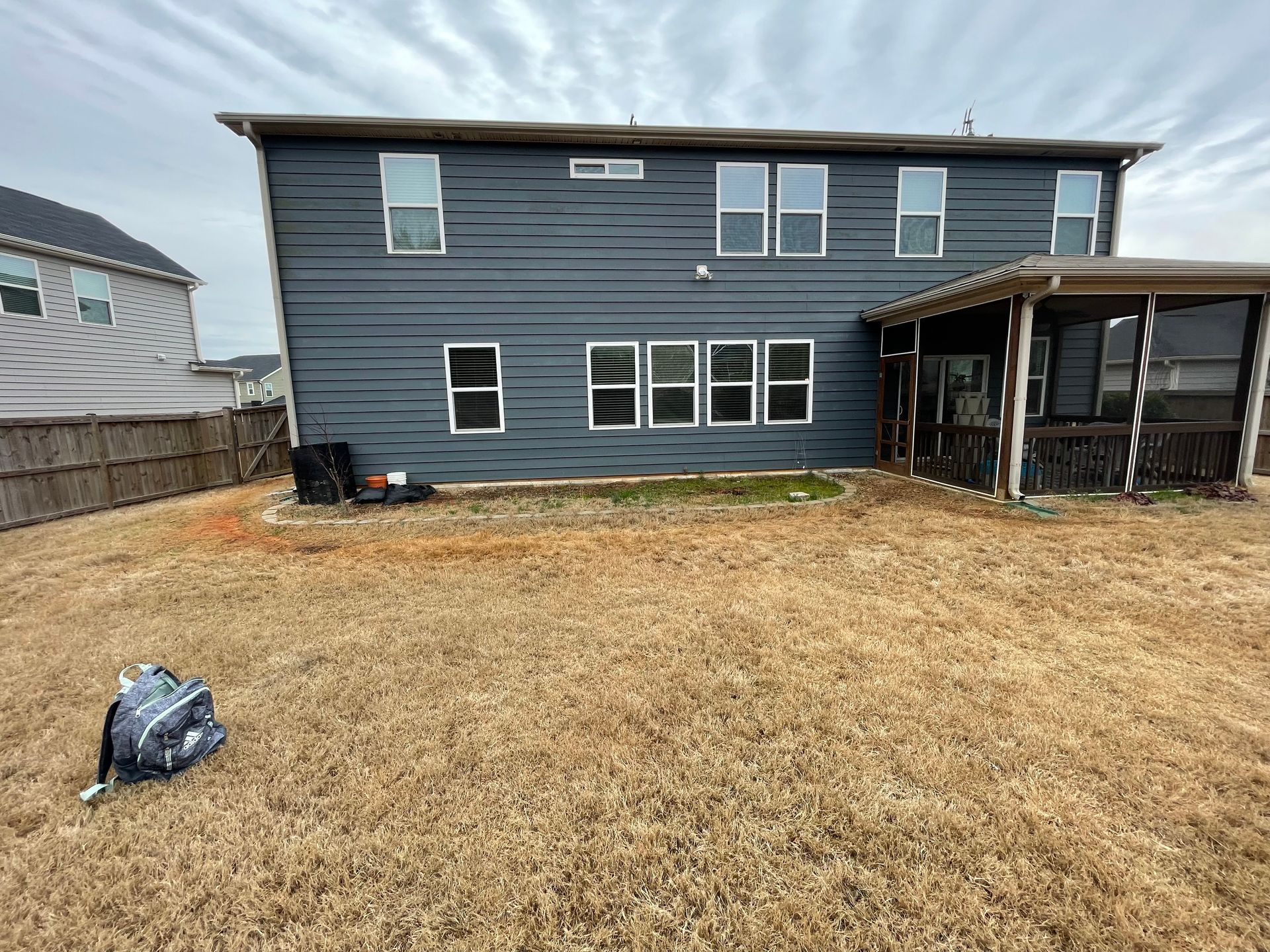 A large house with a screened in porch and a large lawn in front of it.