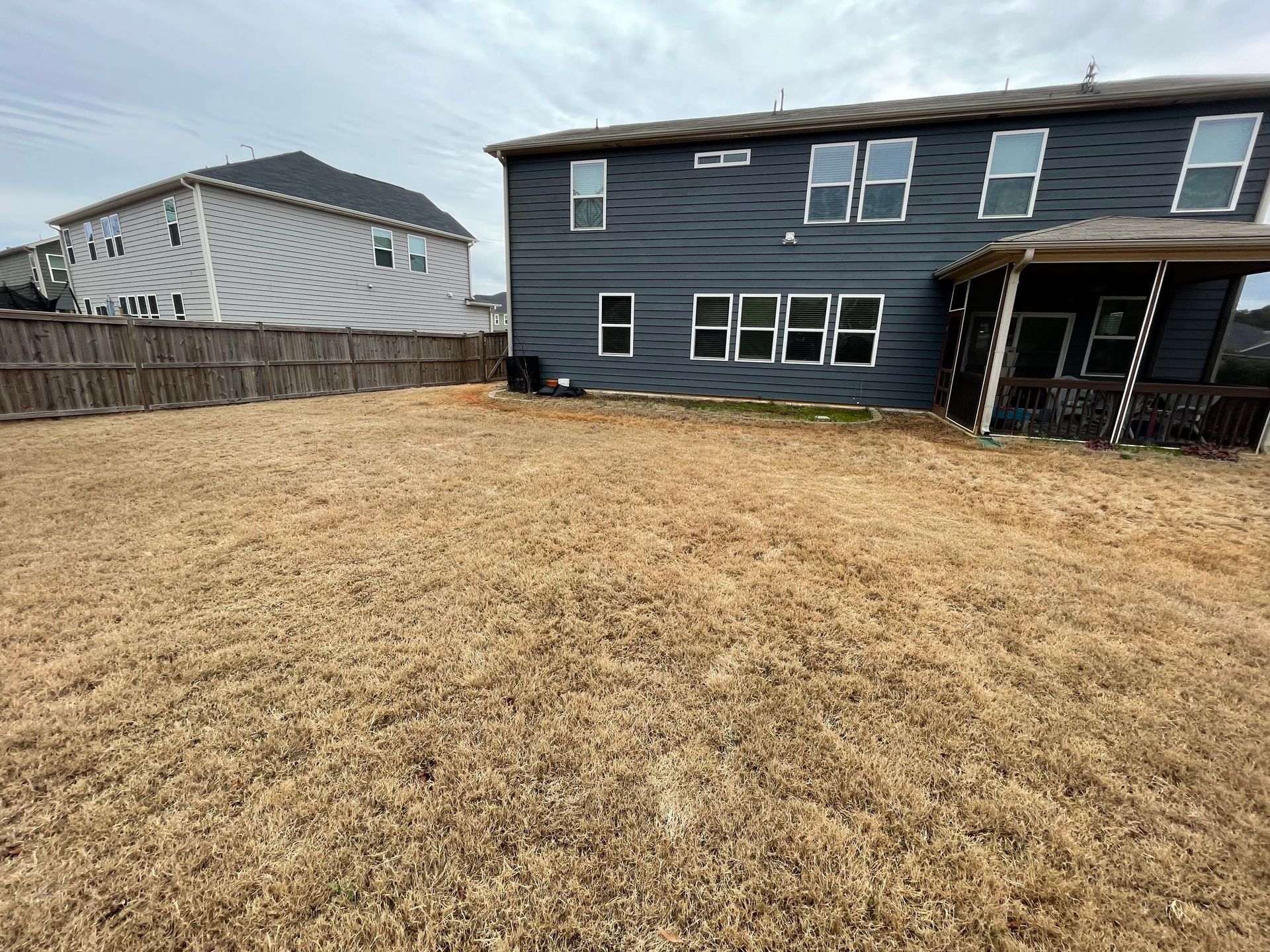 A large house with a fence and a lot of grass in front of it.