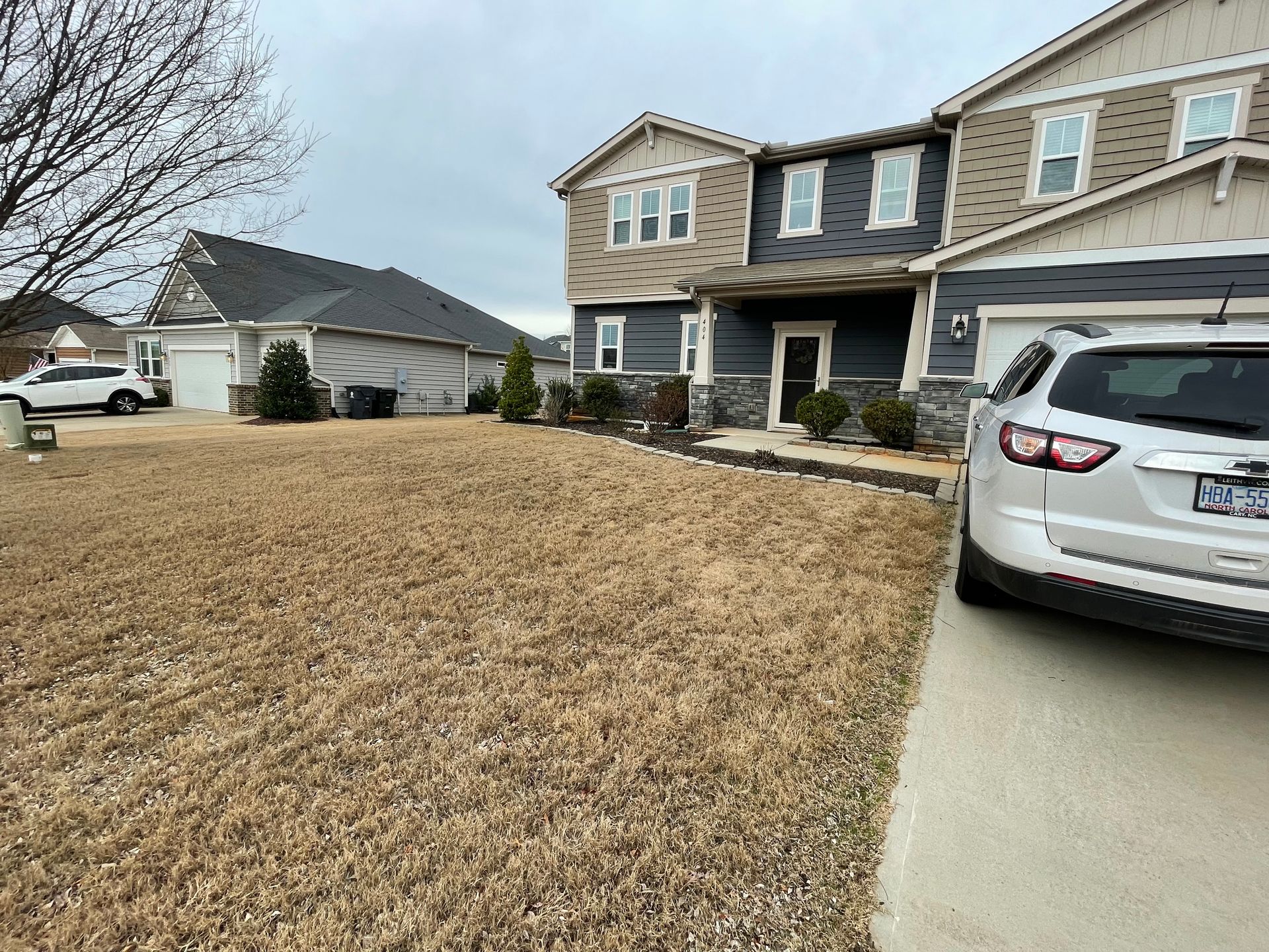 A white suv is parked in front of a large house.