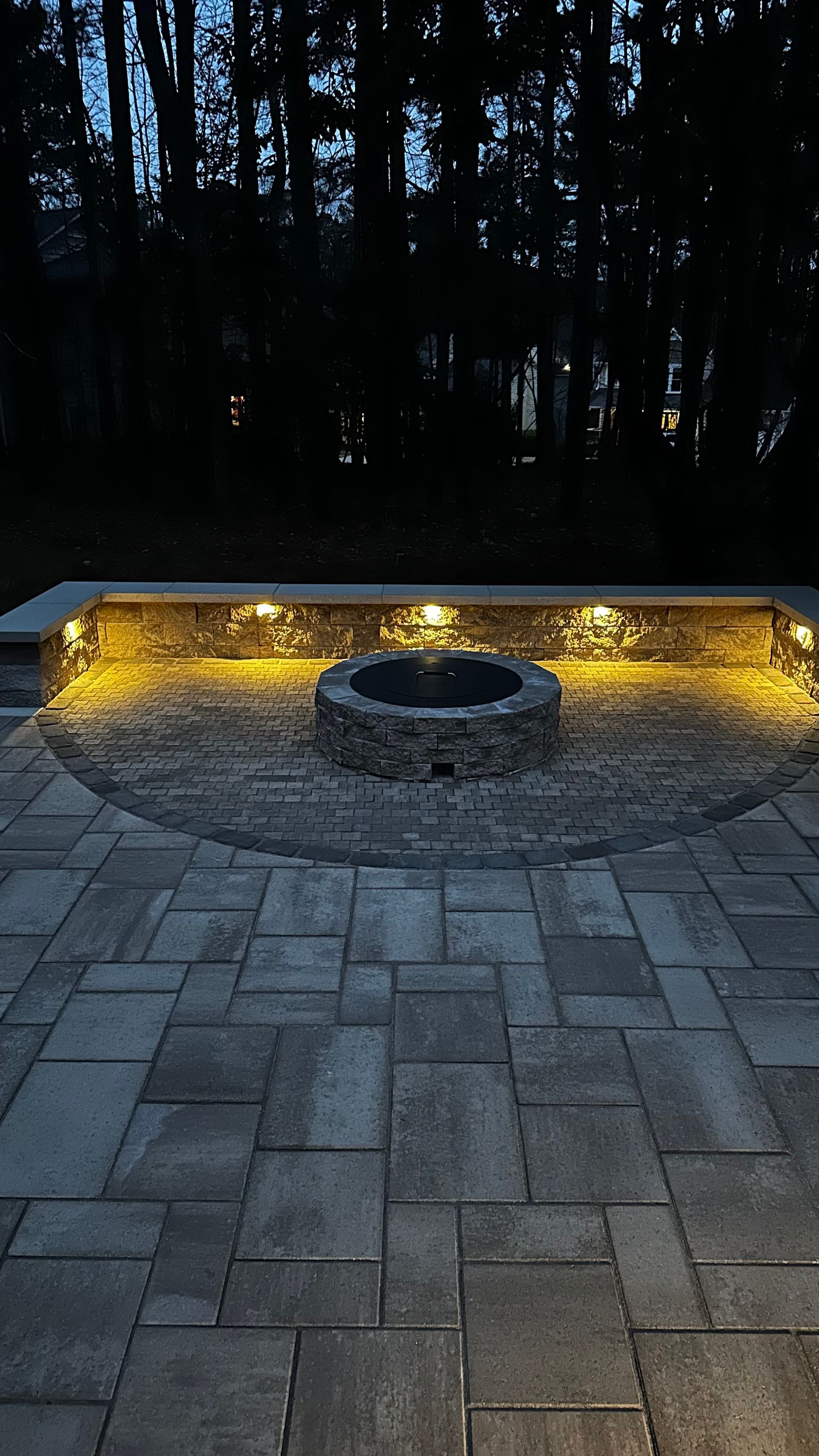 A patio with a fire pit and a playground in the background