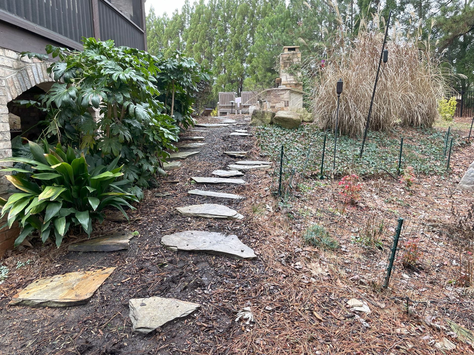A stone walkway leading to a house in a garden.