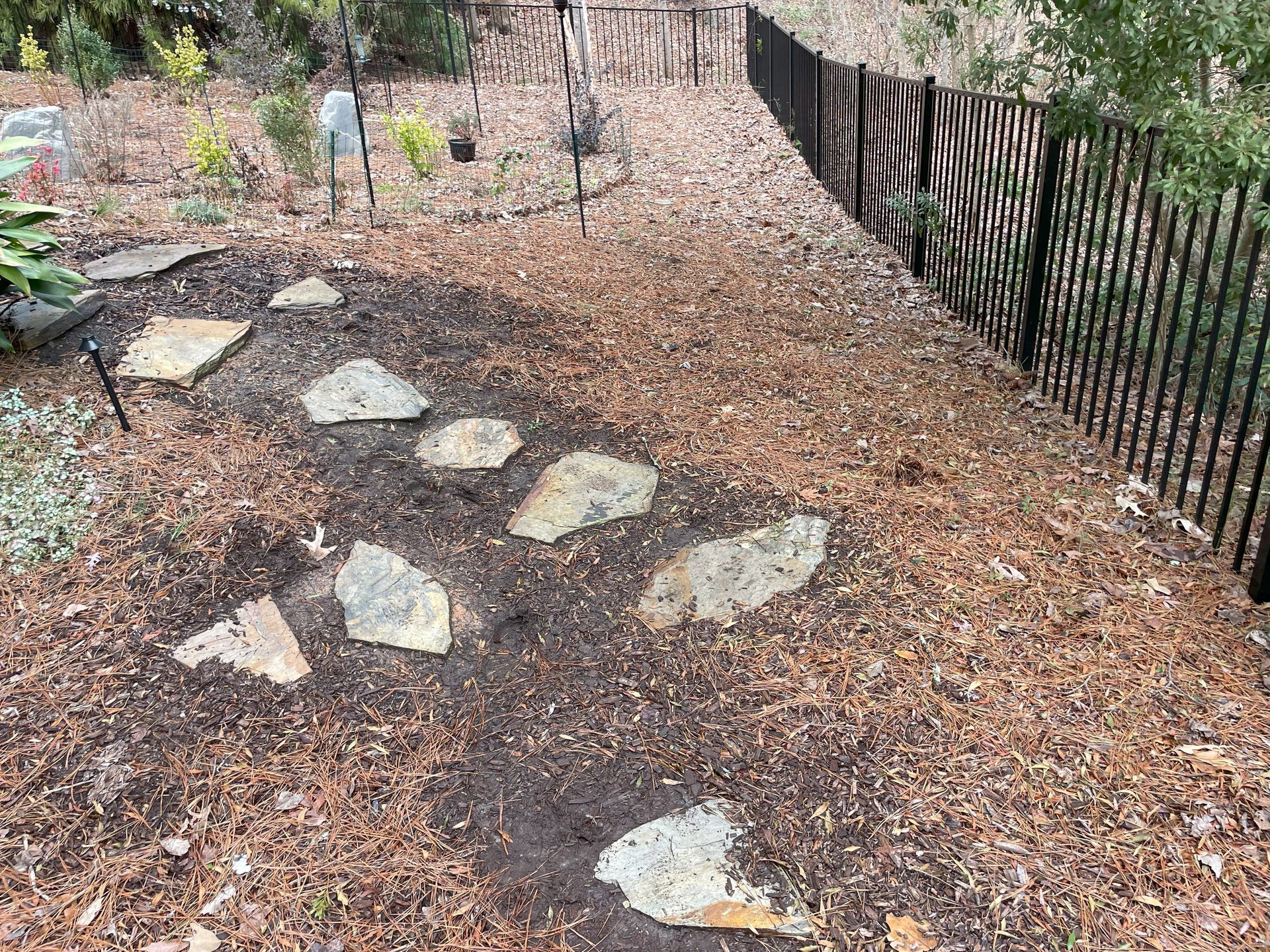 A fence surrounds a garden with rocks and mulch.