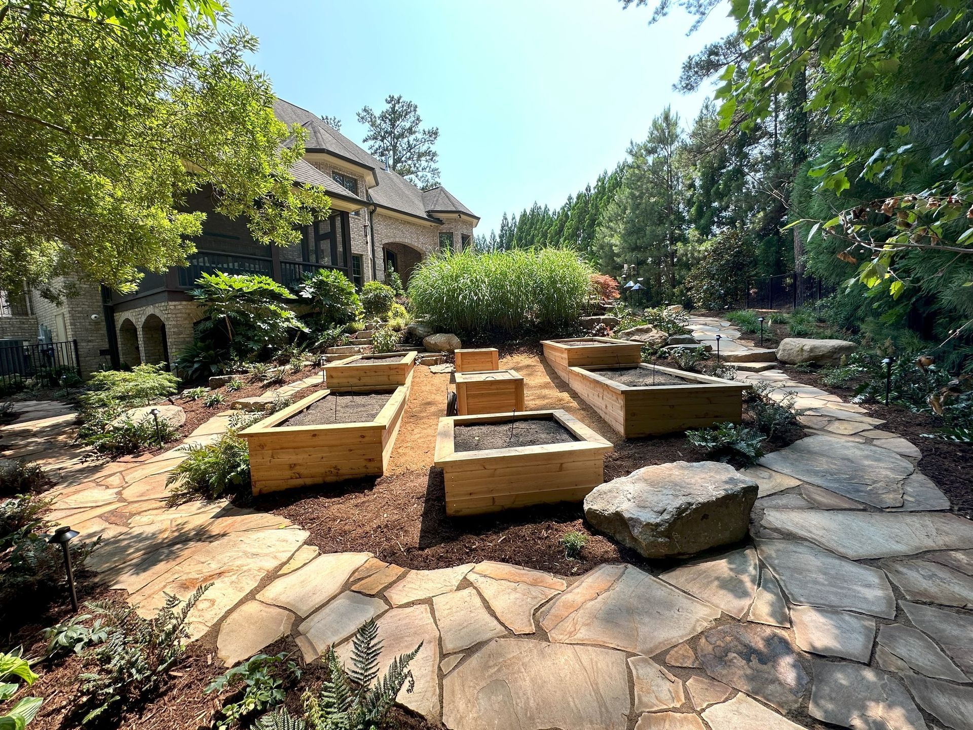 A garden with wooden planters and rocks in front of a house.