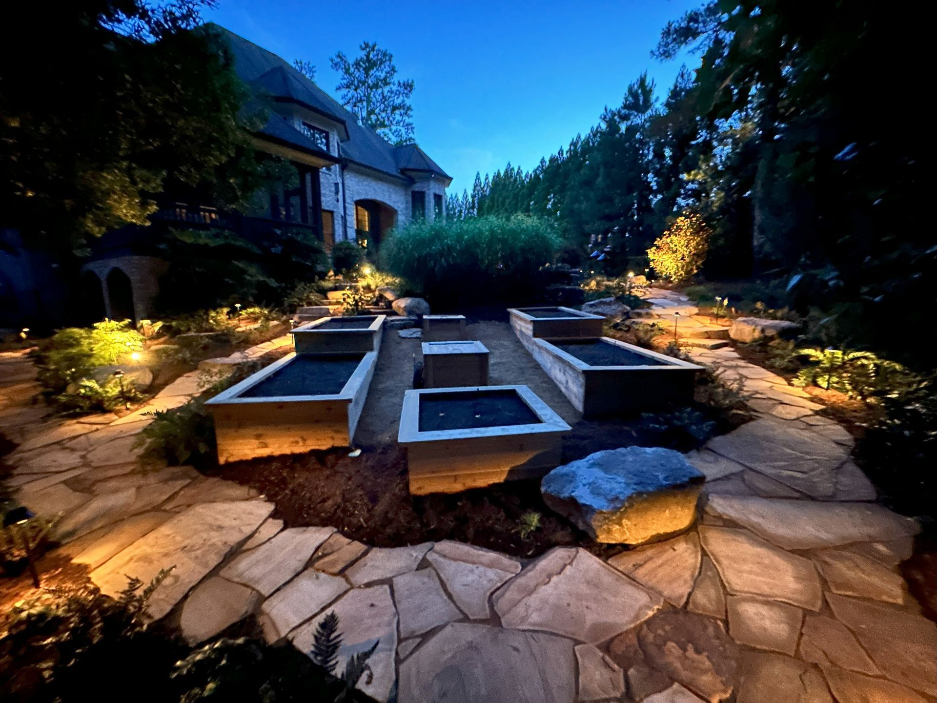 A stone walkway leading to a house at night
