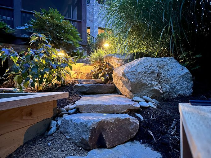 A stone walkway leading to a house at night.