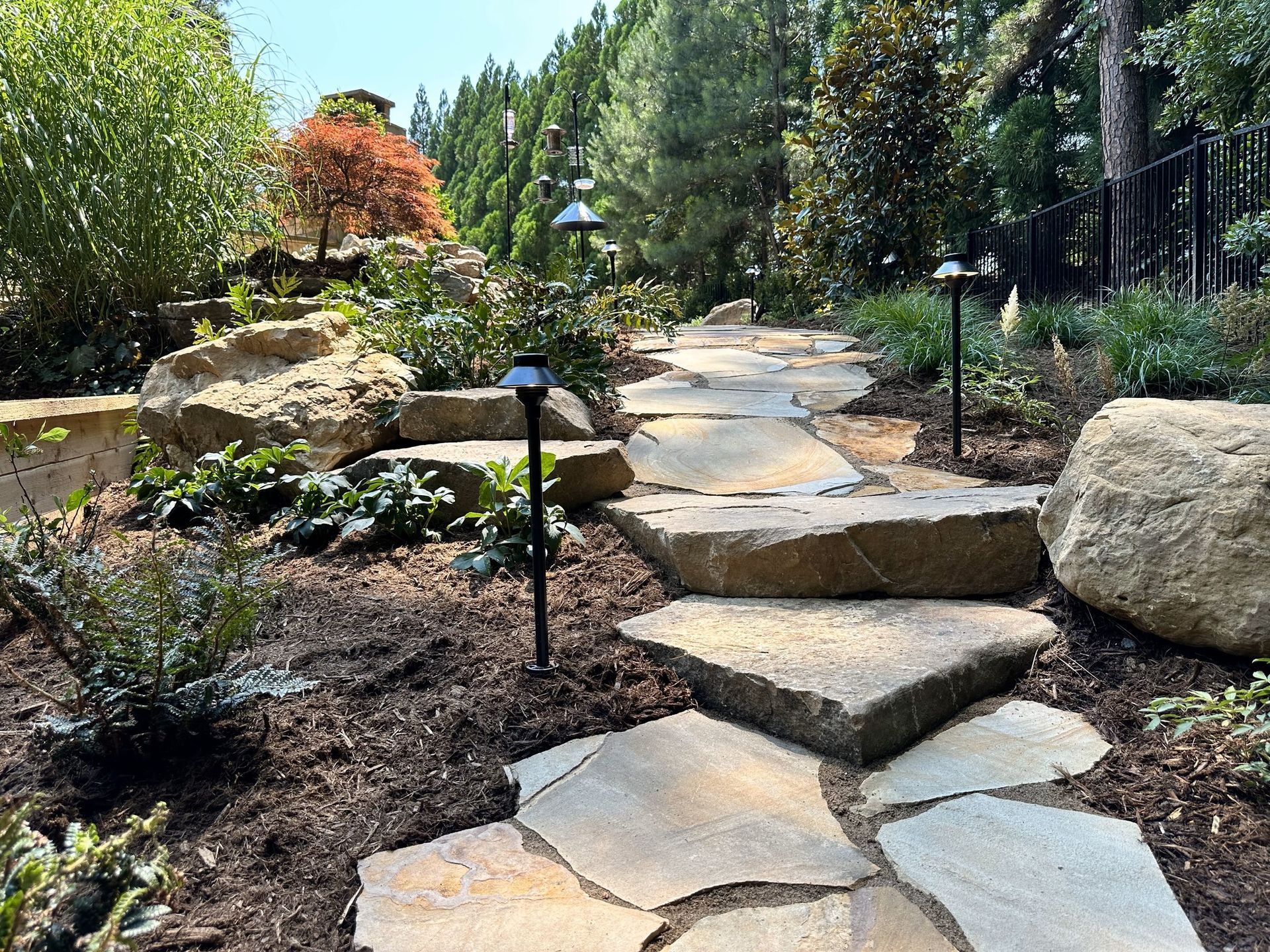 A stone walkway surrounded by rocks and trees in a garden.