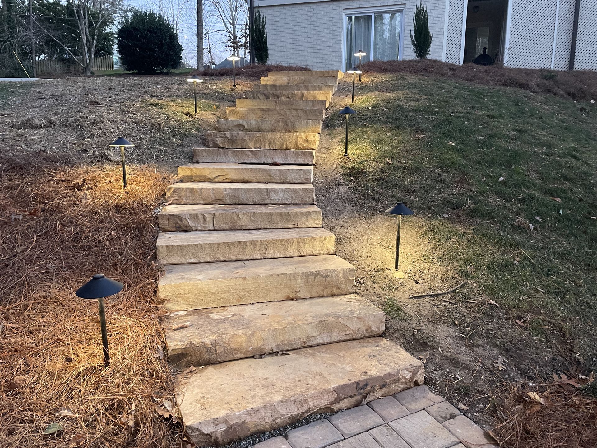 A set of stairs leading up to a house with lights on them.