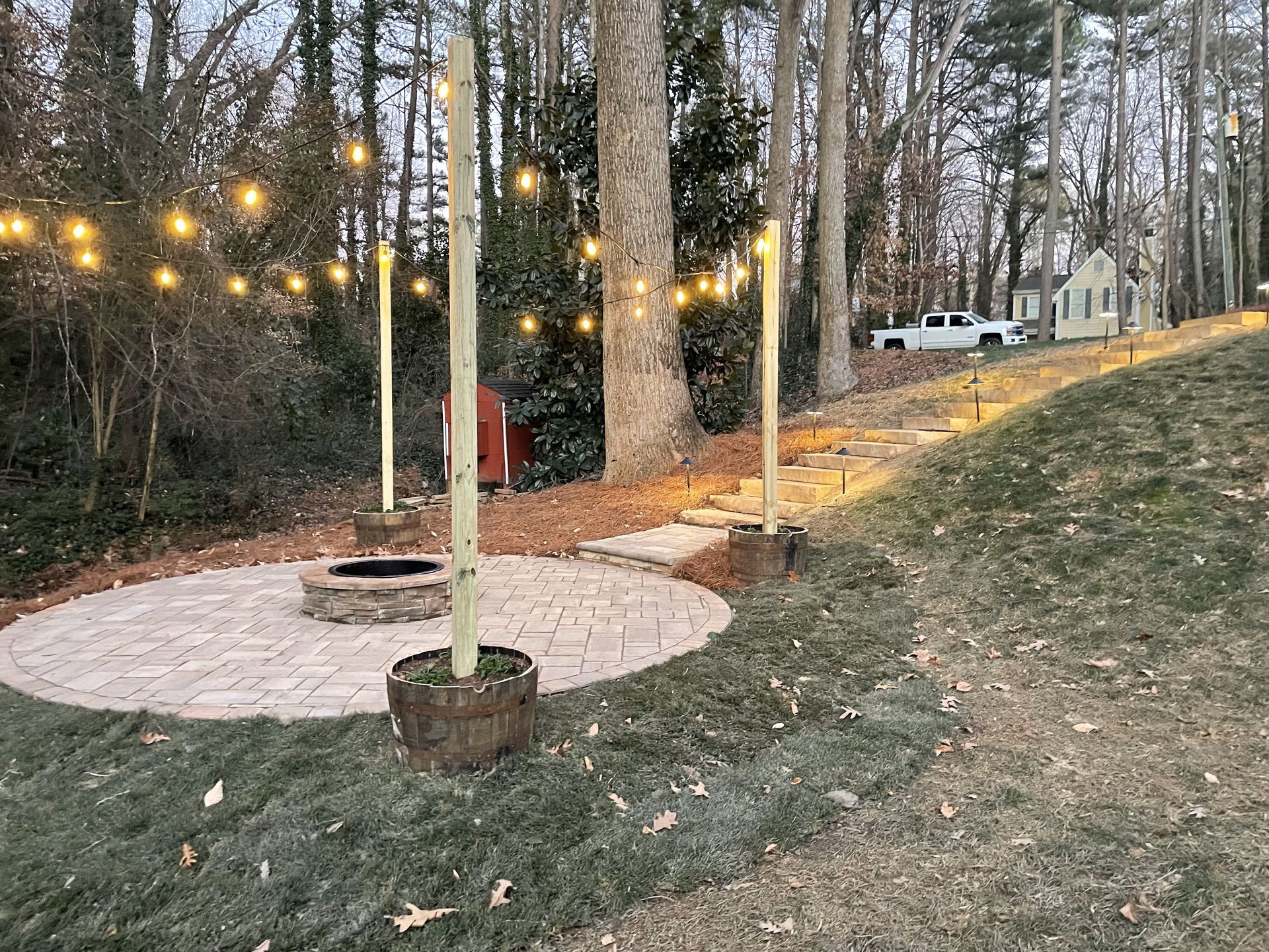 There is a fire pit in the middle of the yard surrounded by trees.