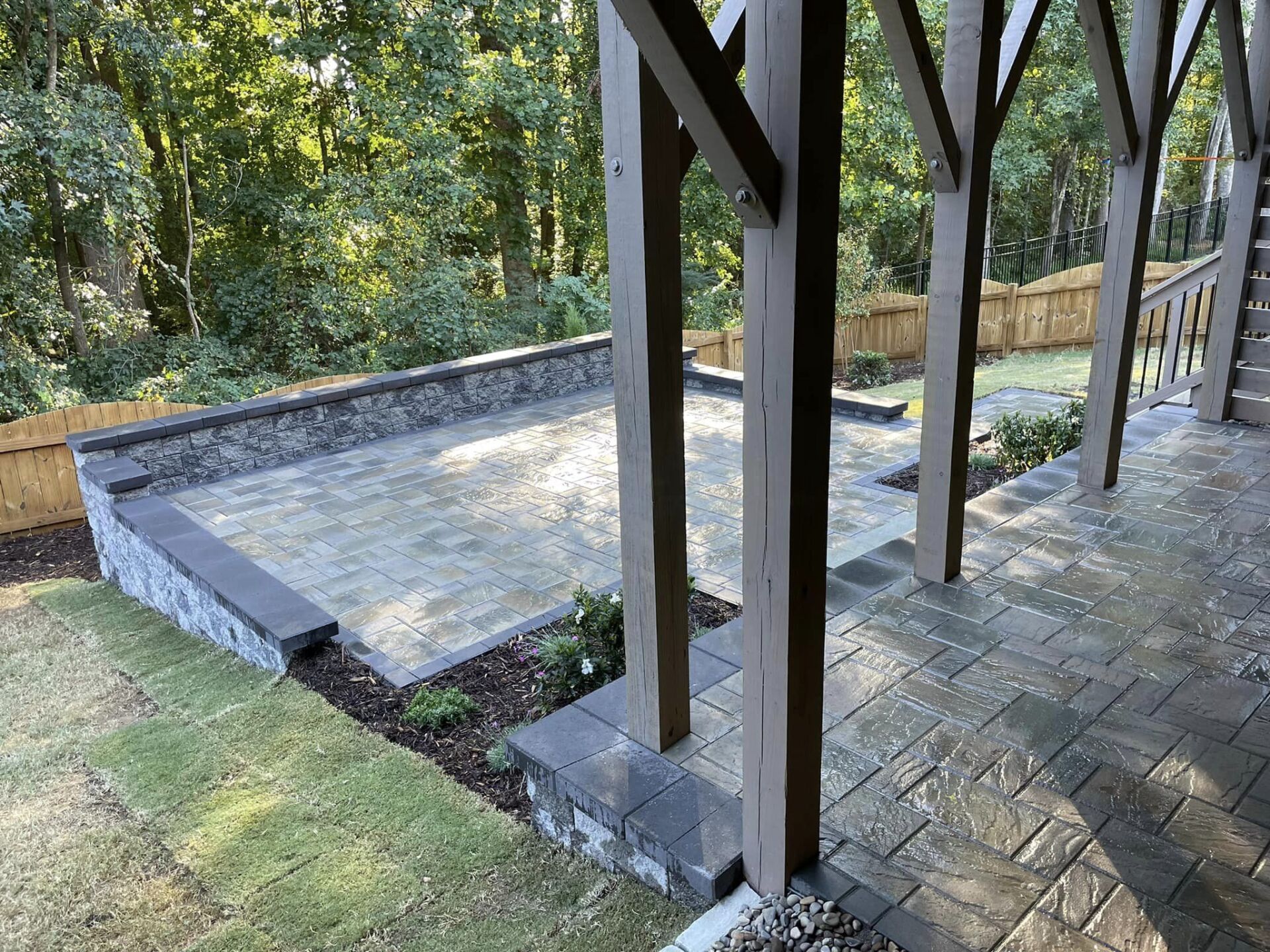 A patio with a wooden fence and trees in the background.