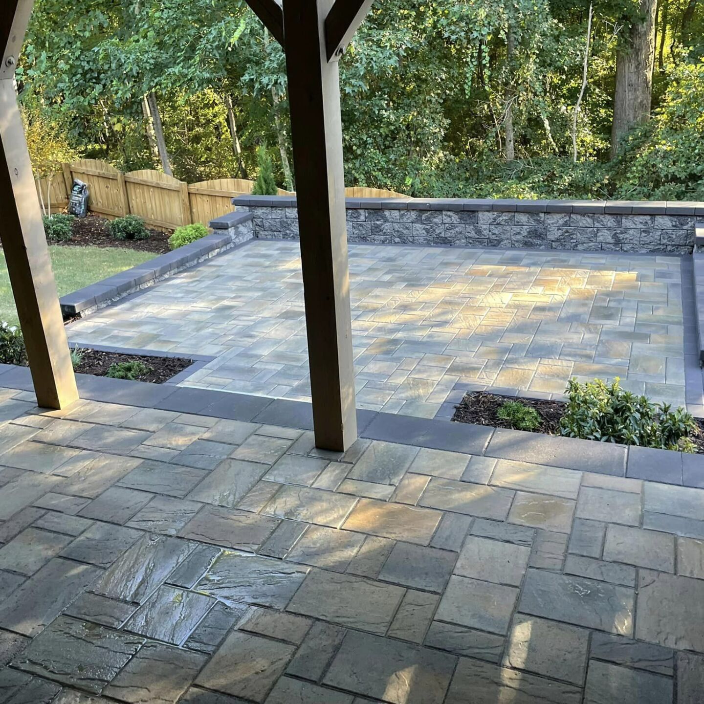 A patio with a stone wall and trees in the background.