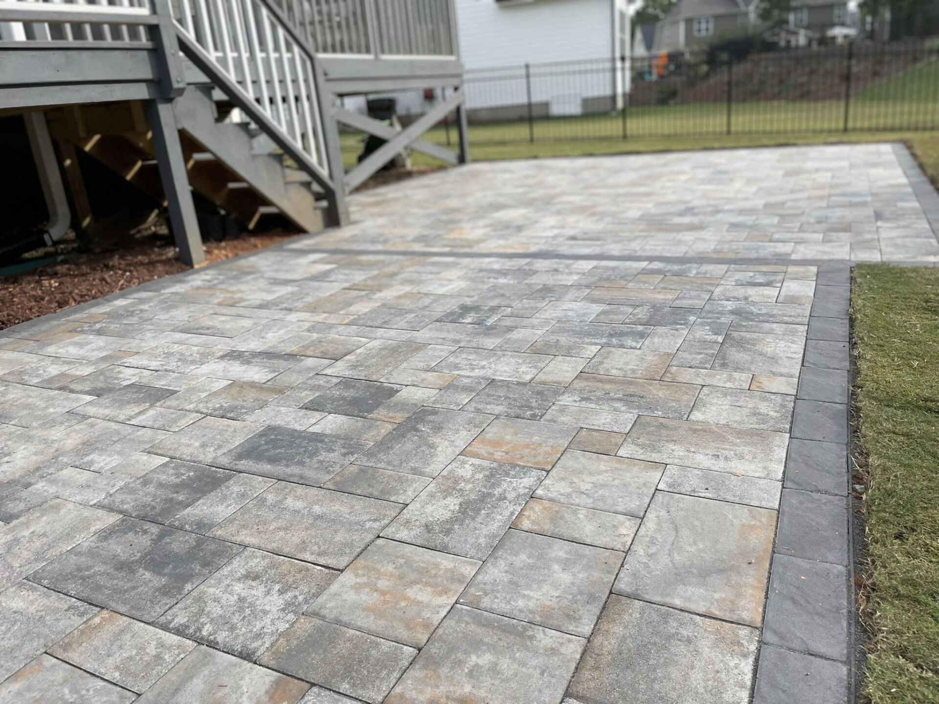 A brick walkway leading to a house with stairs.