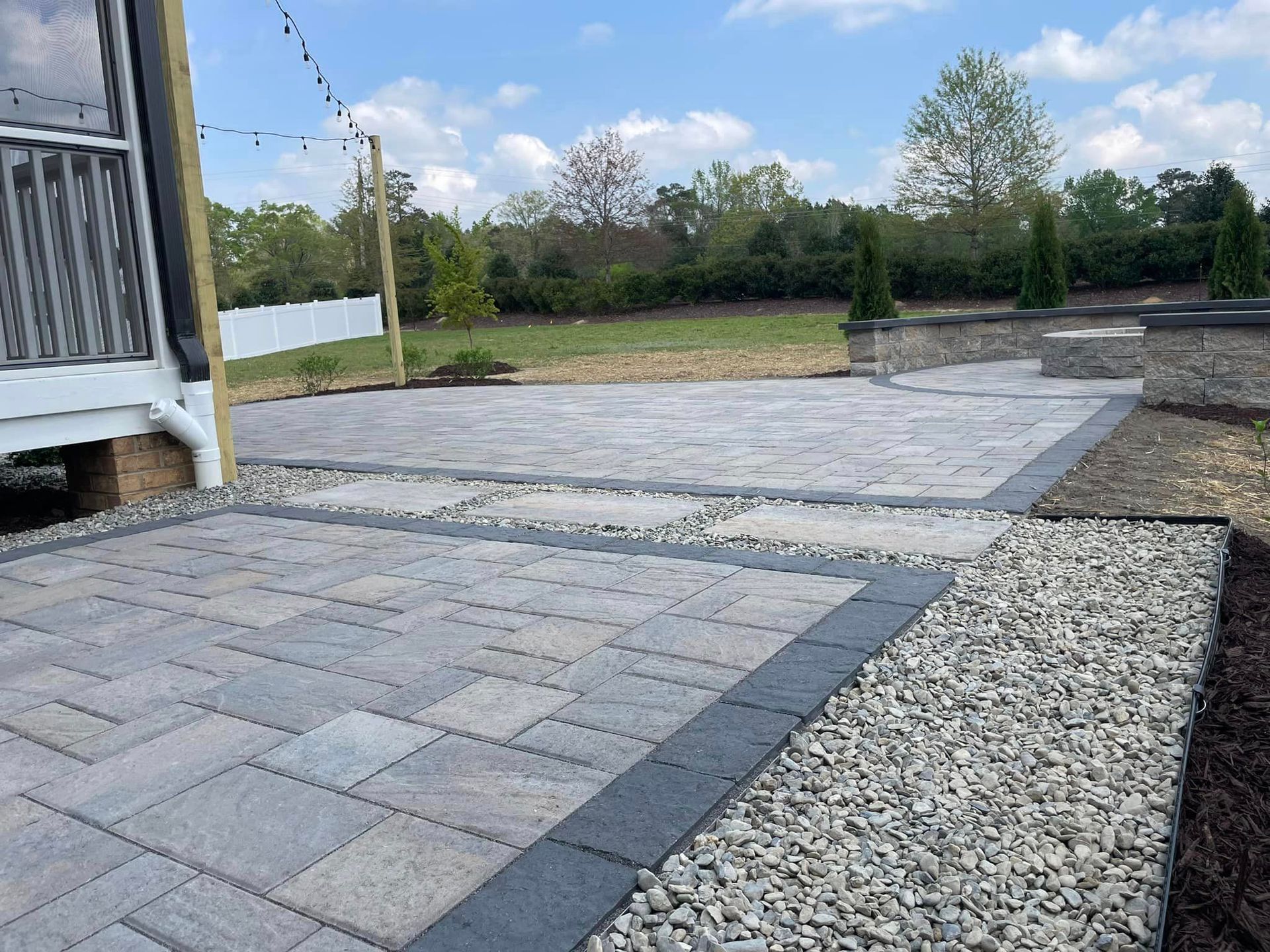 A patio with bricks and gravel in front of a house.