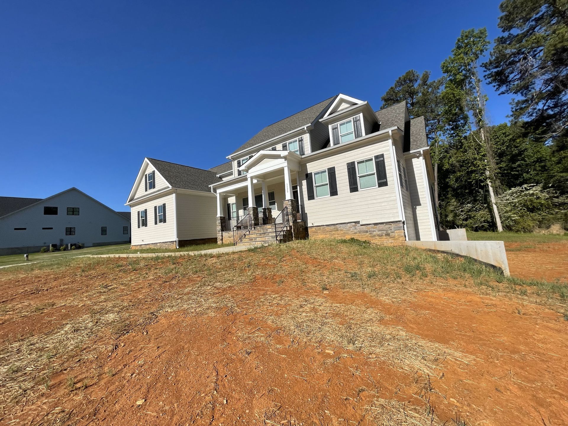 A large white house is sitting on top of a dirt hill.