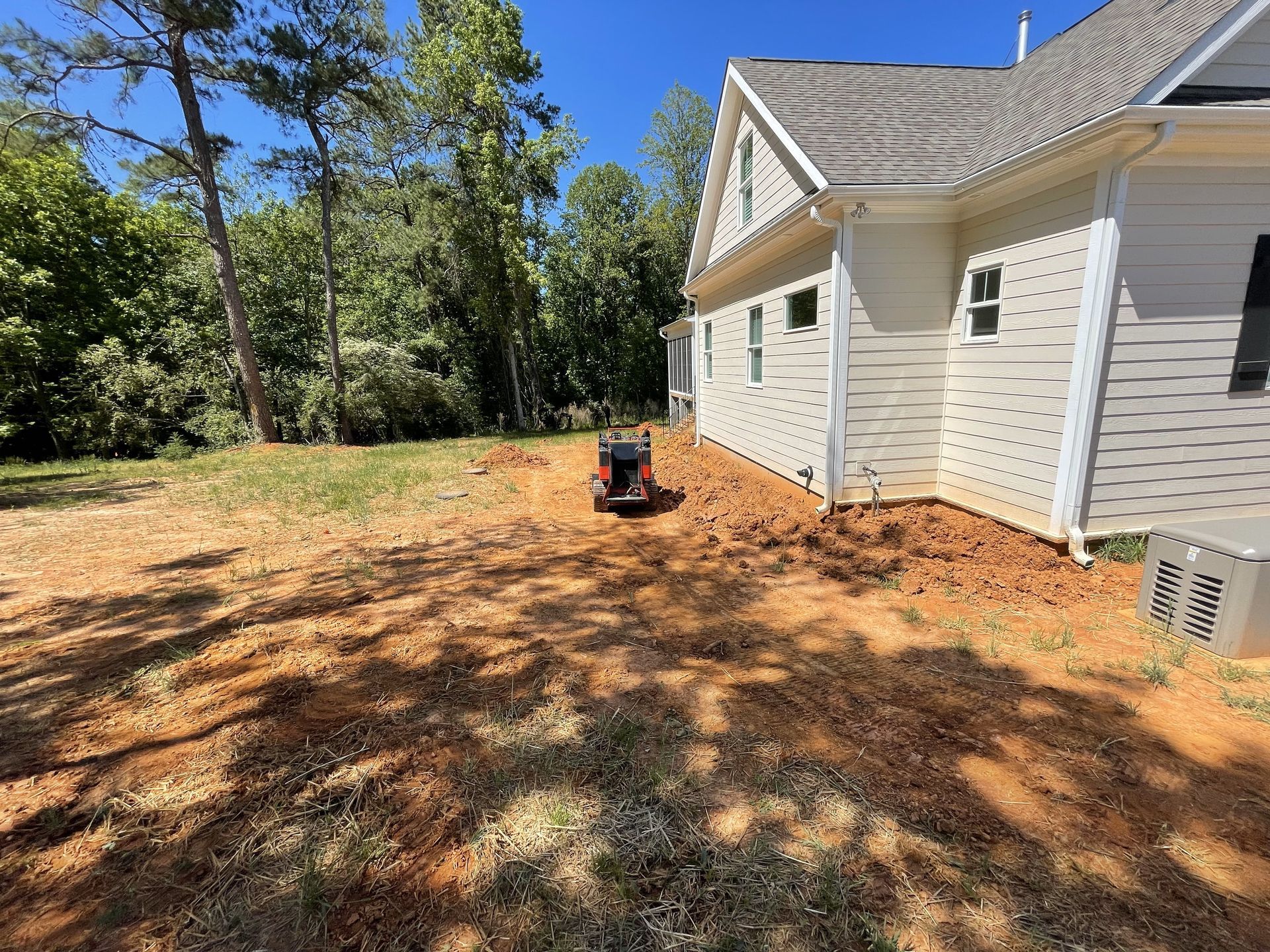 A white house with a stump grinder in front of it.