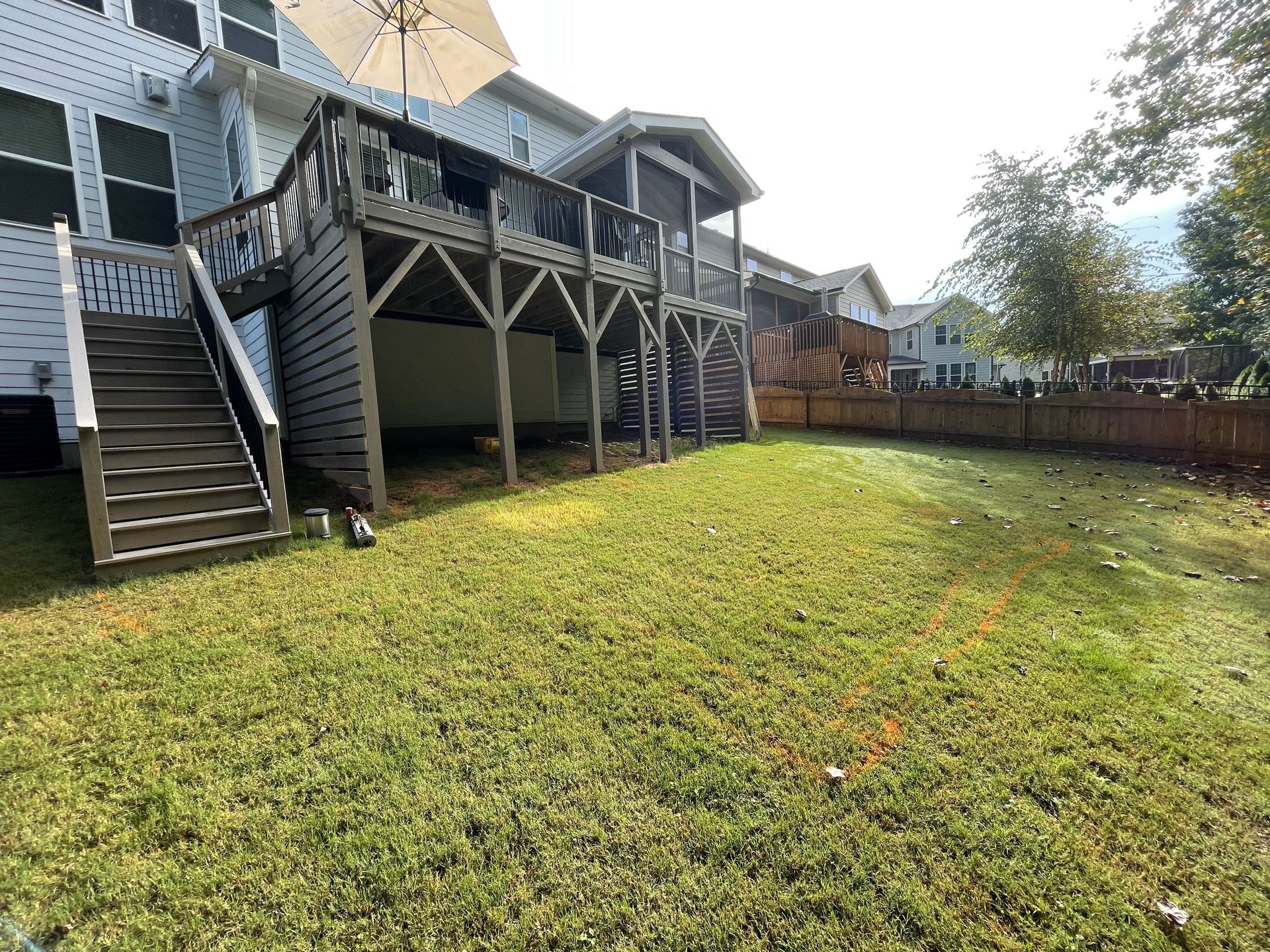 A large lawn in front of a house with a deck and stairs.