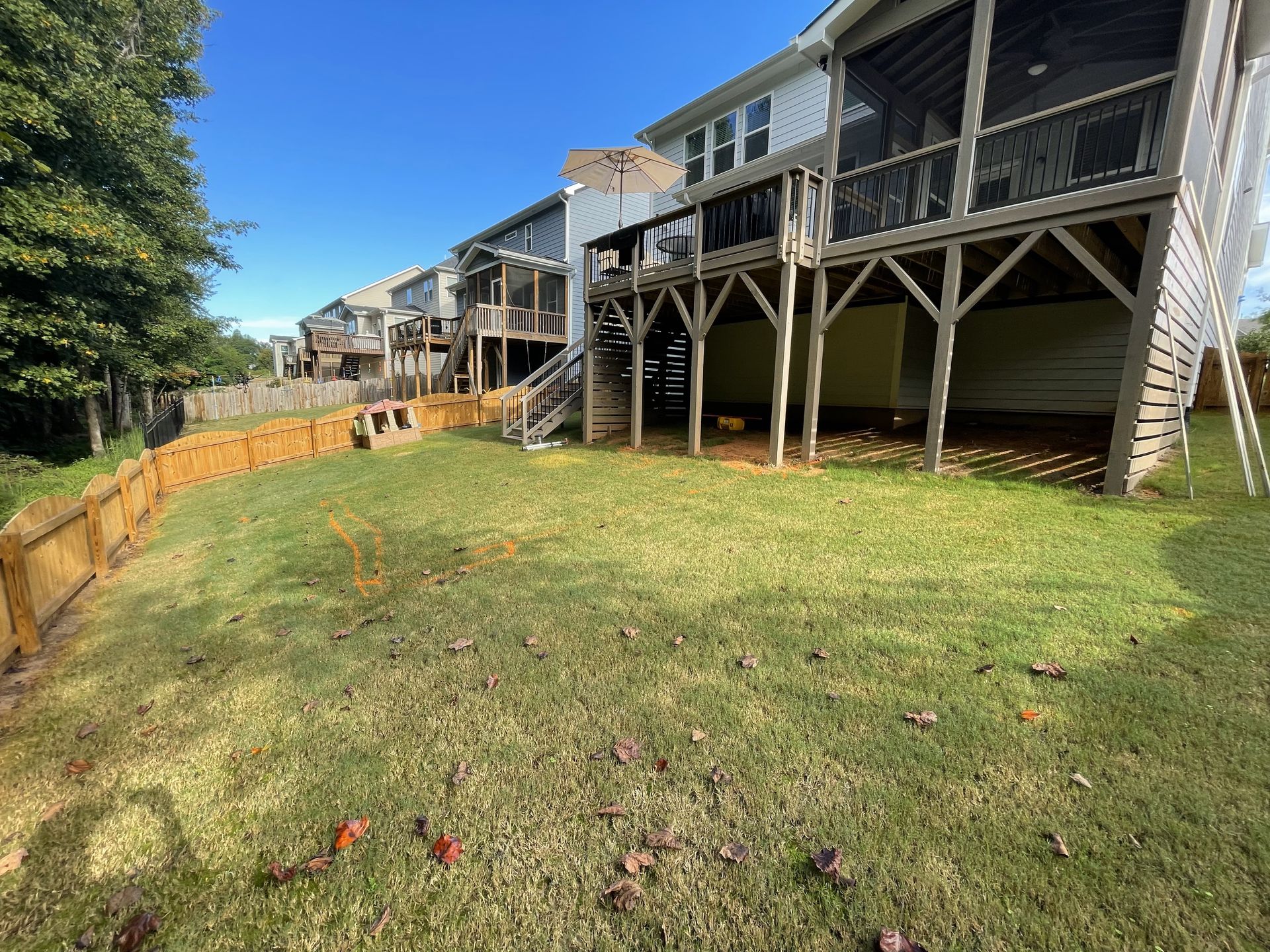 The backyard of a house with a wooden fence and a large deck.
