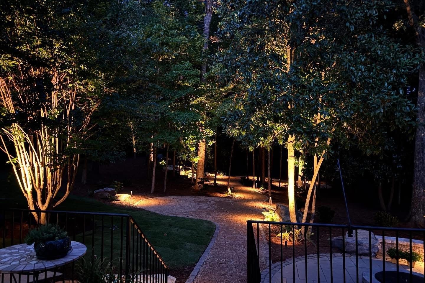 A stone walkway is lit up at night in a garden.