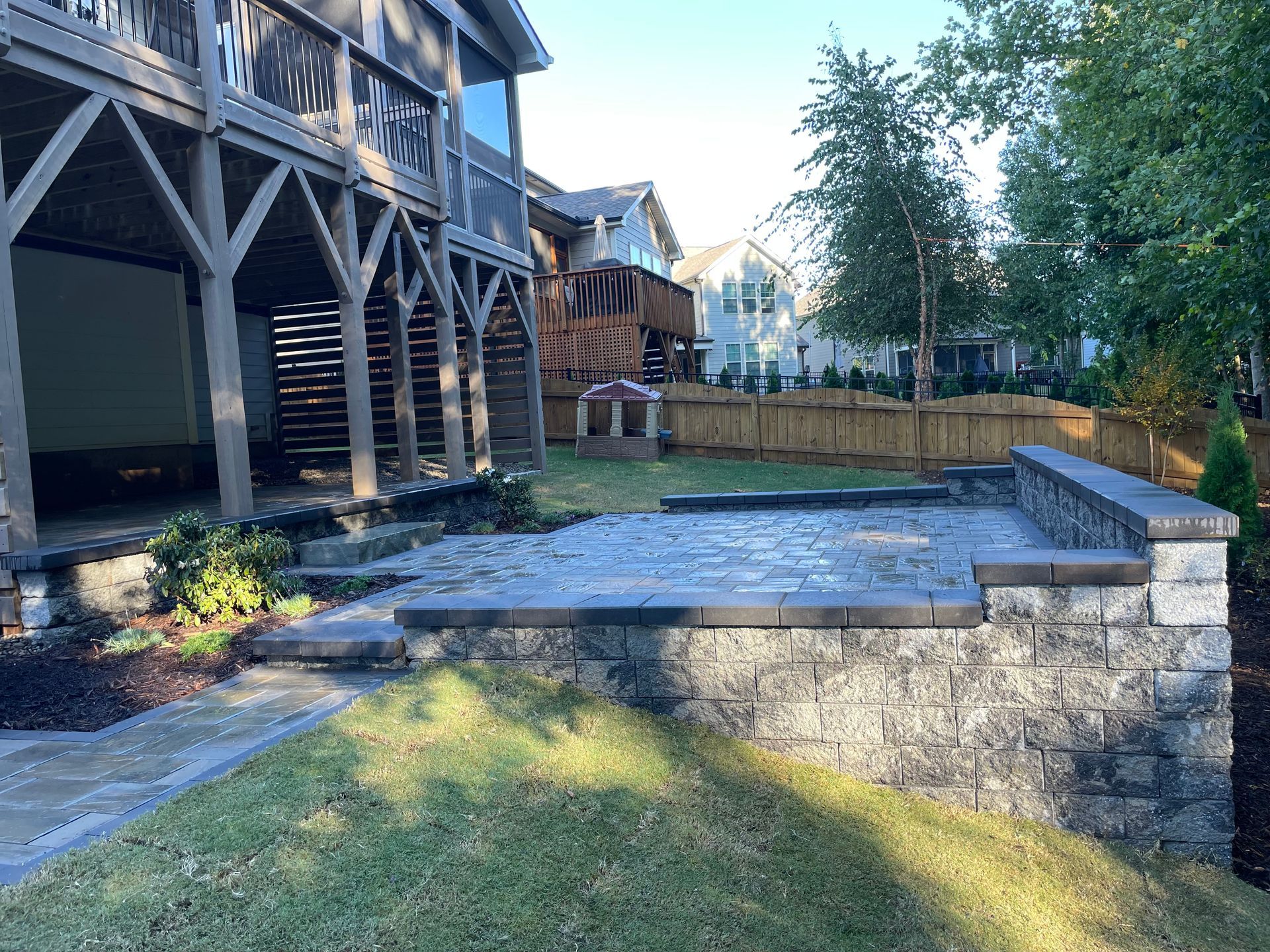 A backyard with a stone wall , steps , and a house in the background.