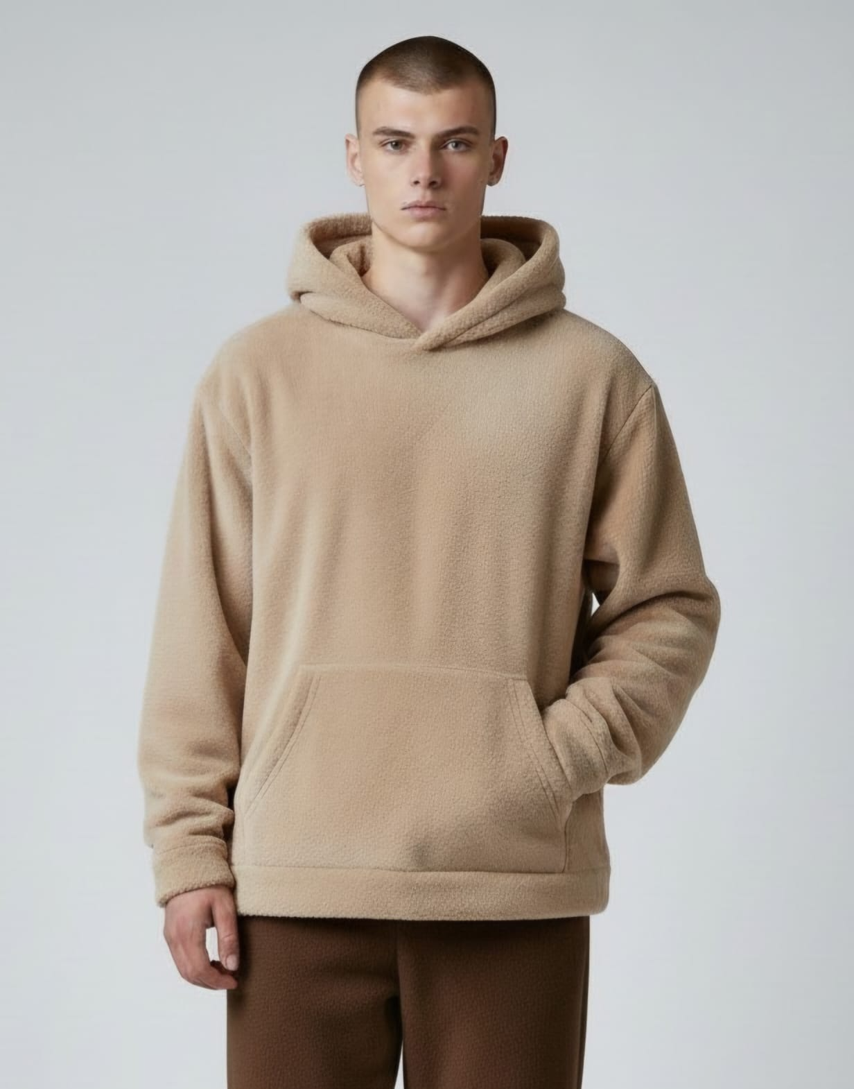 Modelo con sudadera color crema y vaqueros azules sobre un fondo gris liso.