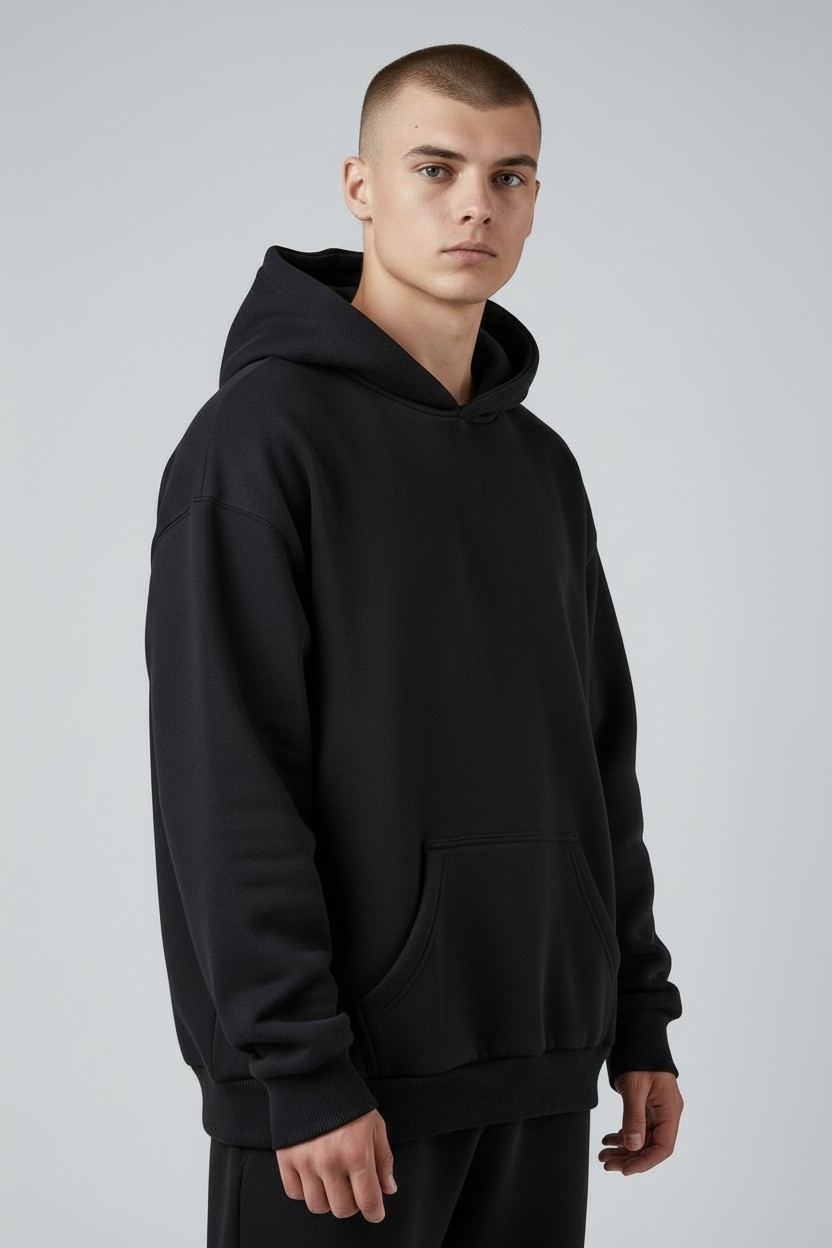 Persona con una sudadera extragrande color crema de pie sobre un fondo gris claro.