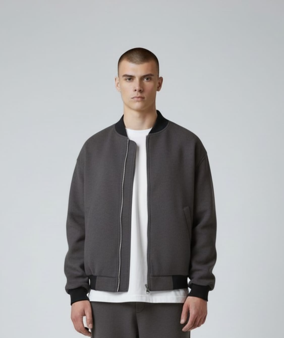 Persona con chaqueta marrón sobre camisa blanca sobre fondo gris
