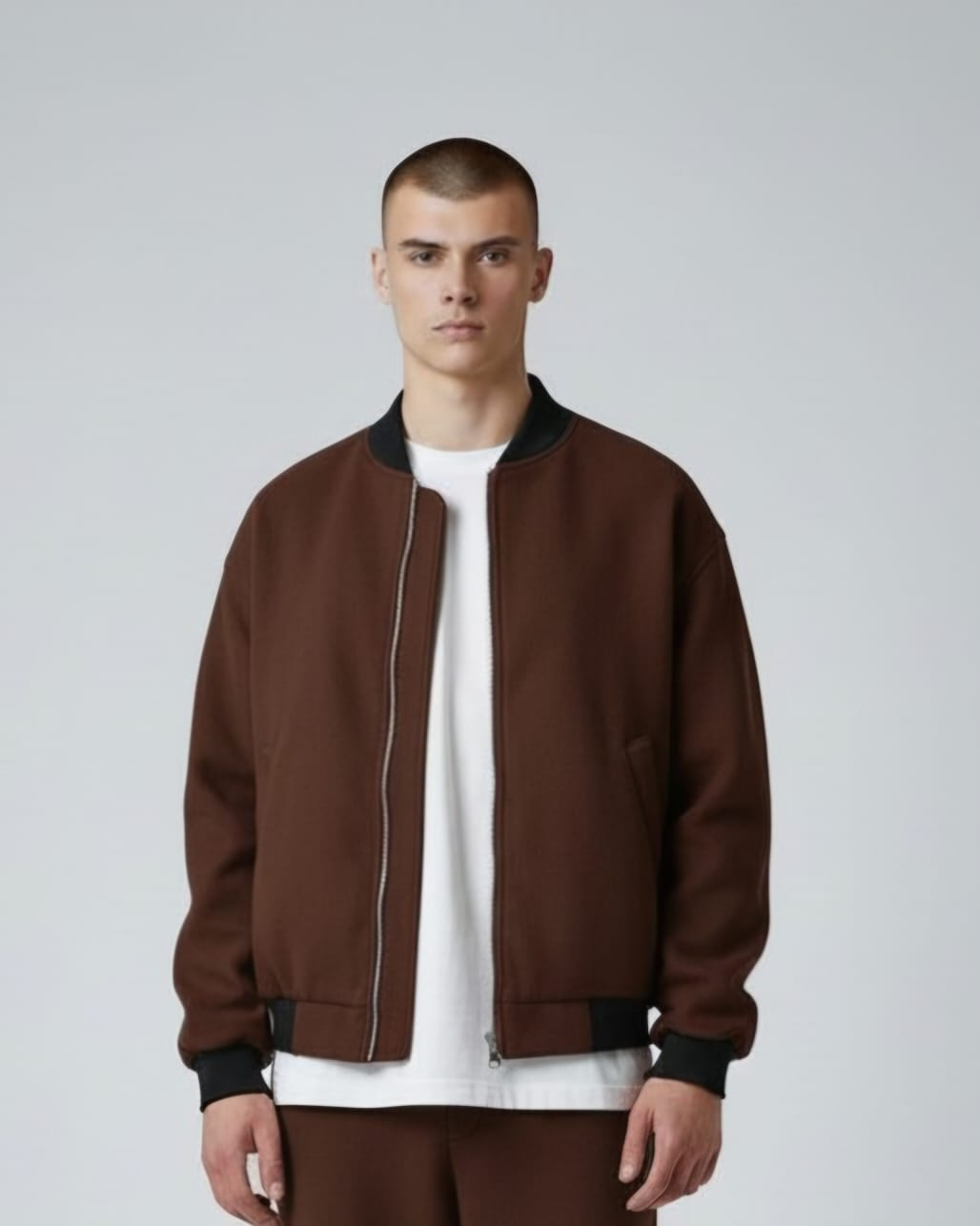 Persona con chaqueta marrón sobre camisa blanca sobre fondo gris