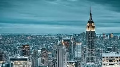 An aerial view of a city skyline at night with the empire state building in the foreground.