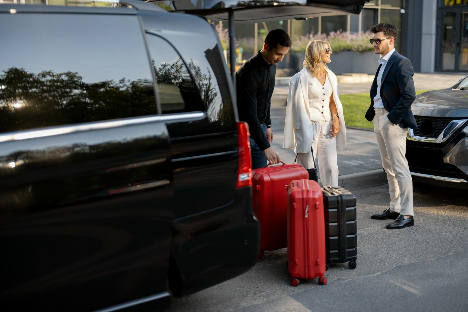 A man is loading luggage into the back of a black van.