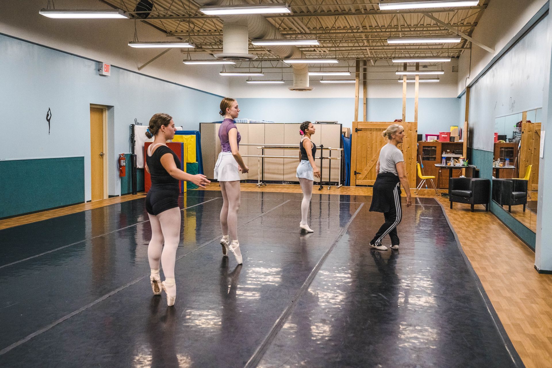 A group of ballerinas are practicing in a dance studio.