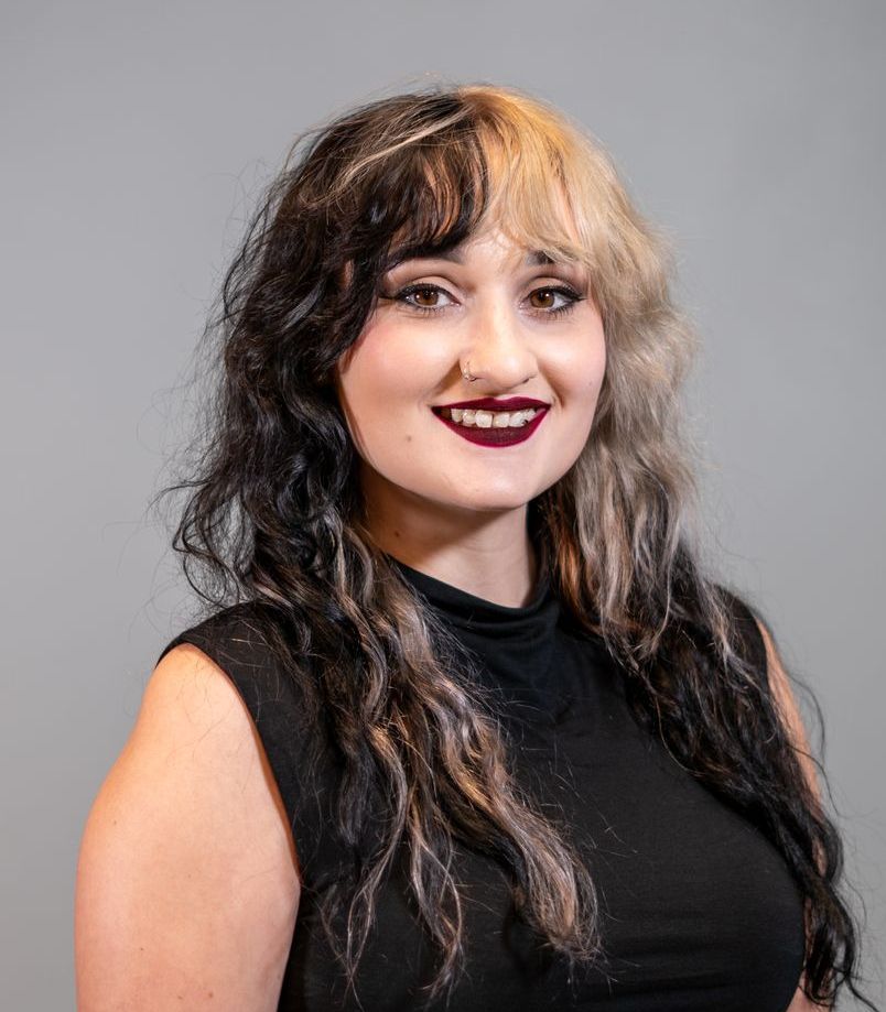 A woman with long hair and red lipstick is wearing a black tank top.