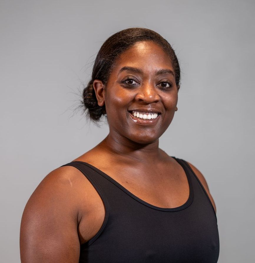 A woman in a black tank top is smiling for the camera.