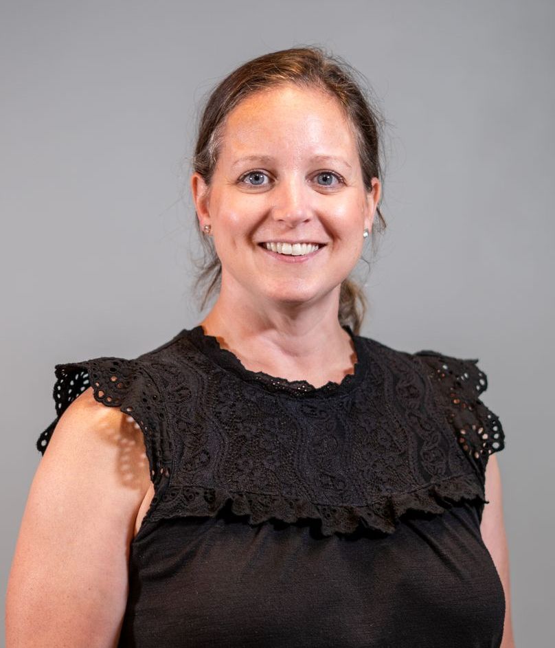 A woman in a black lace top is smiling for the camera.