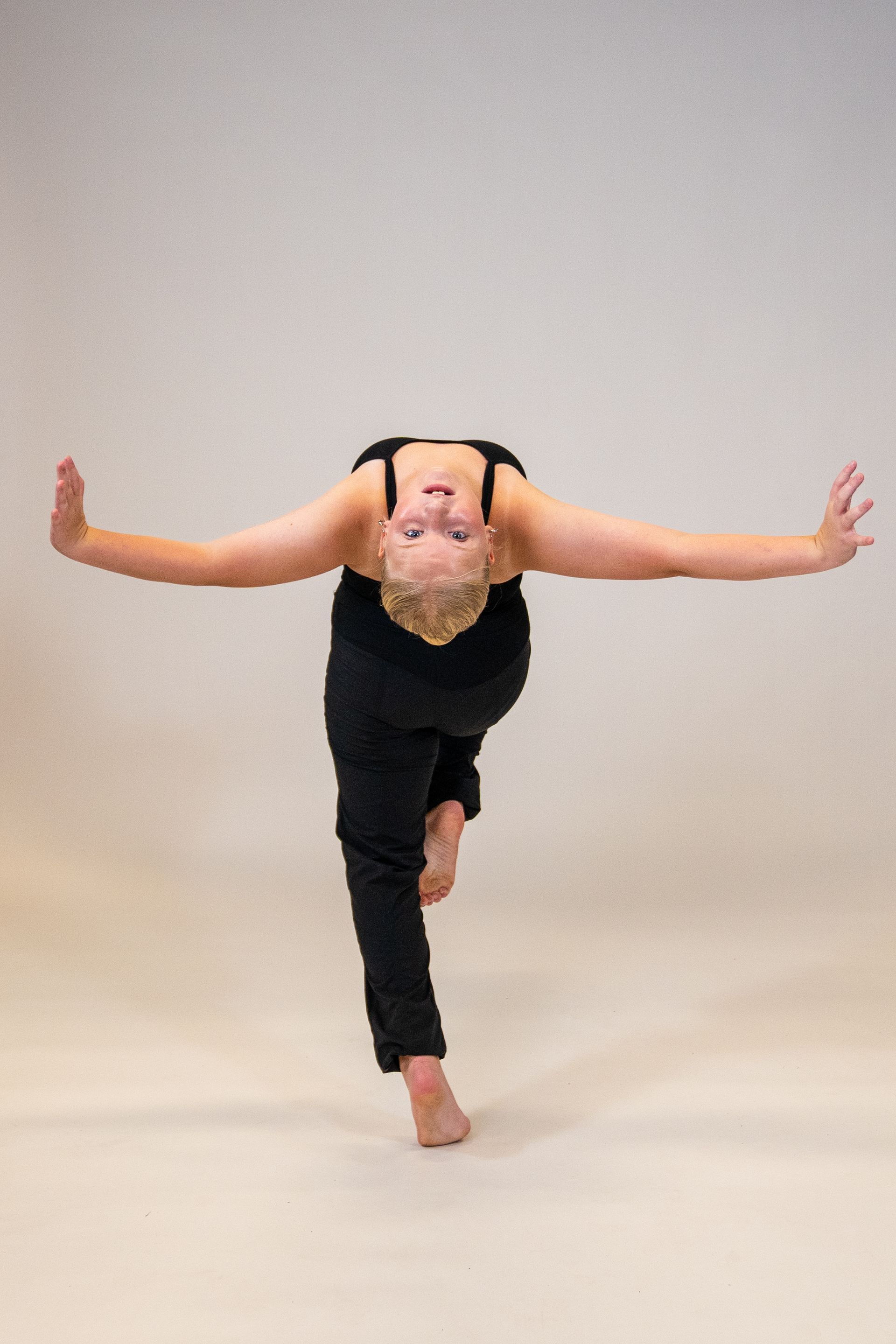 A woman is standing on one leg with her arms outstretched.