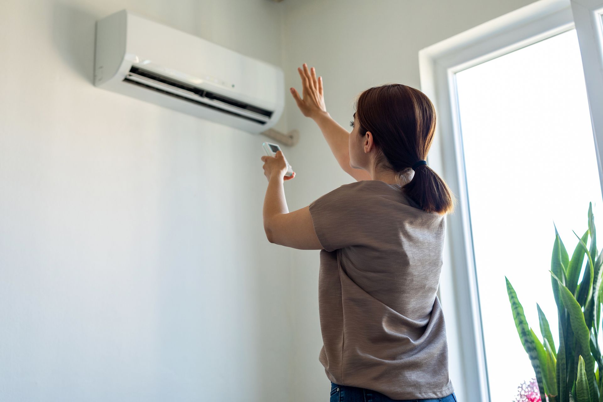 Woman turning on an air conditioner.