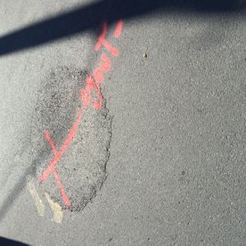 Surface asphaltée marquée à la peinture rouge en aérosol autour d'une zone ovale.