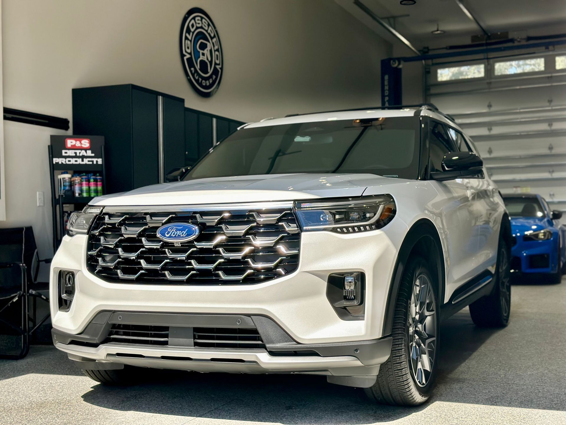White Ford Explorer SUV parked inside a garage; blue Ford car visible in the background.