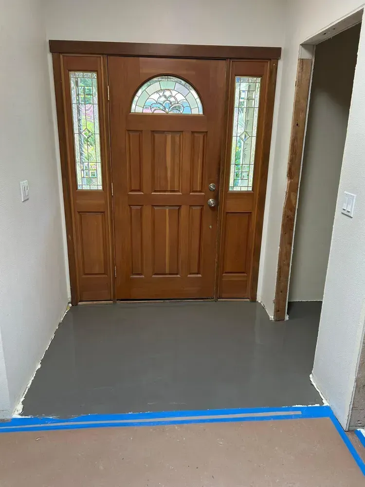 A hallway with a wooden door and a stained glass window.