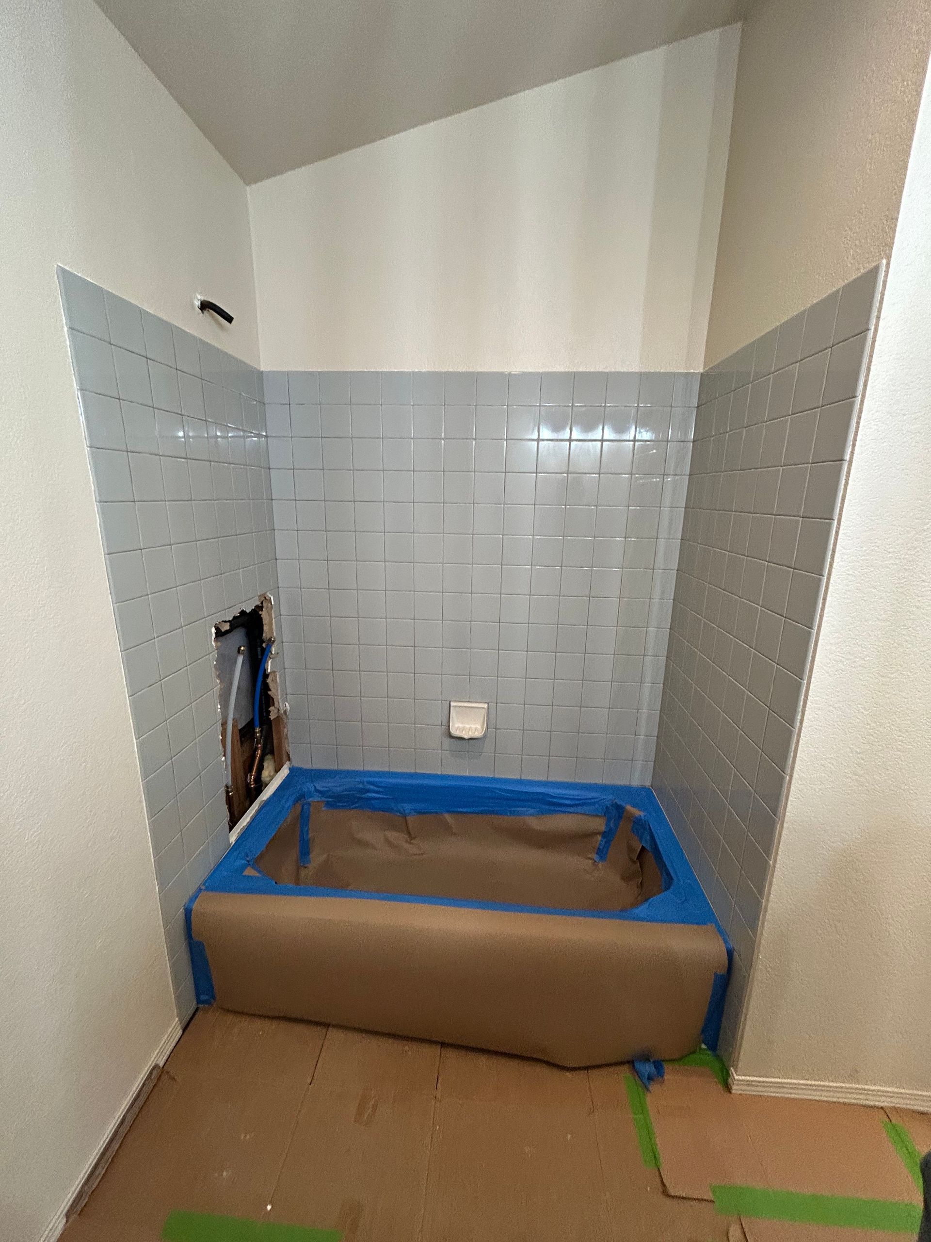 A bathtub is taped to the wall in a bathroom.