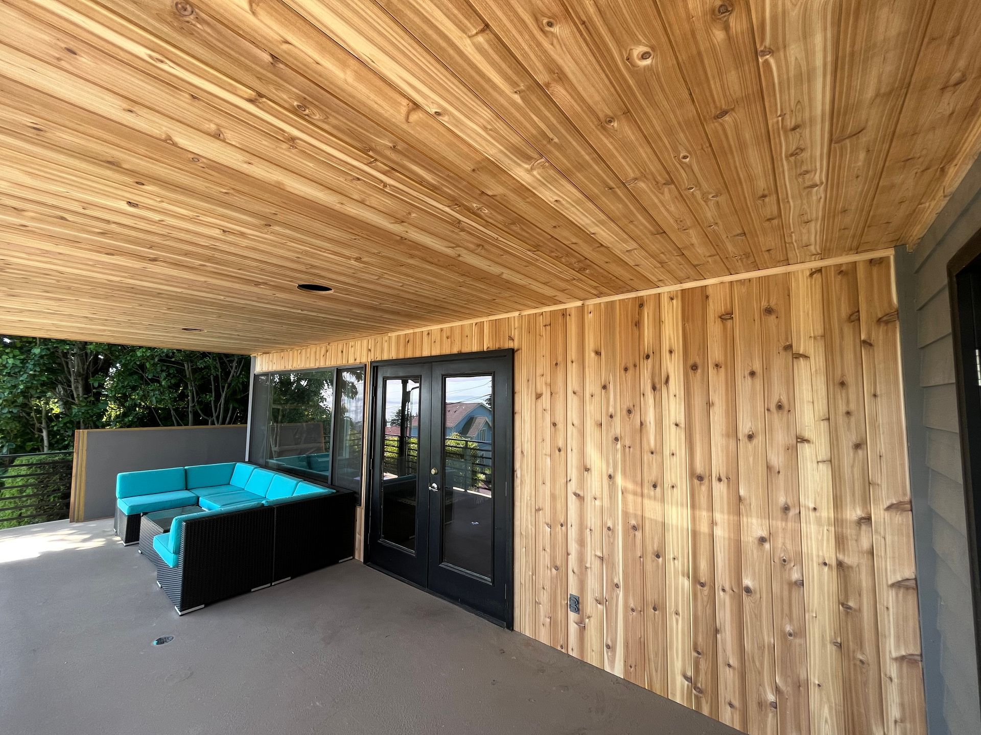 A wooden porch with a couch and sliding glass doors.