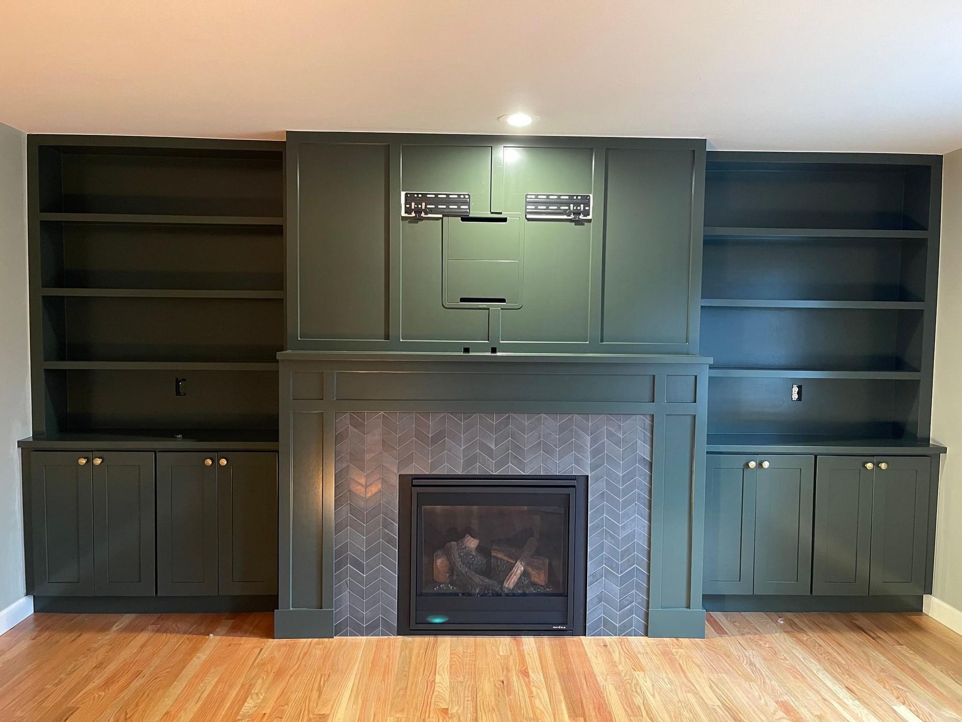 A living room with a fireplace and green cabinets.