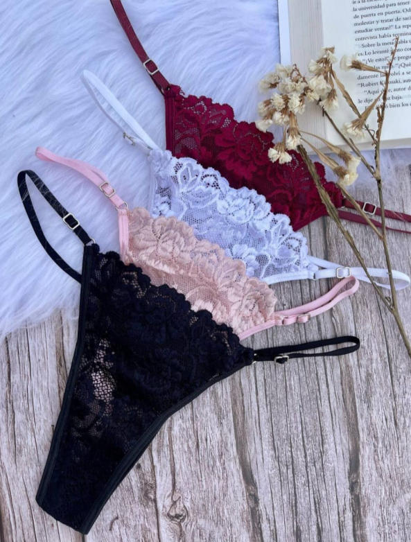 Conjunto de lencería de encaje burdeos: sujetador y tanga sobre una superficie de madera con un libro y flores.