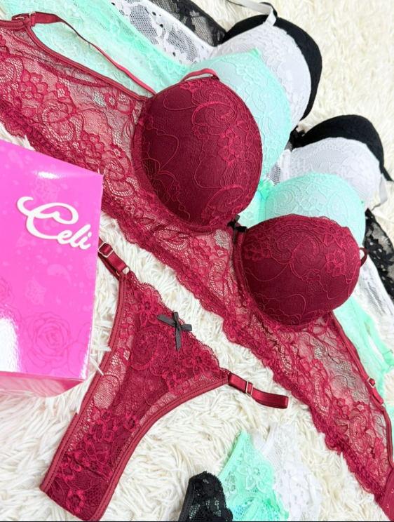 Conjunto de lencería: sujetador y tanga de encaje burdeos, con otros sujetadores en menta, negro y blanco. Caja Celie rosa.