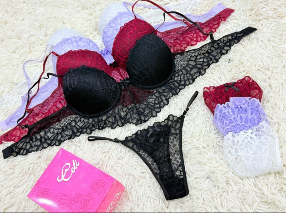 Conjunto de lencería: sujetador y tanga de encaje morado, bragas de encaje negro, rojo y blanco sobre una superficie blanca esponjosa.