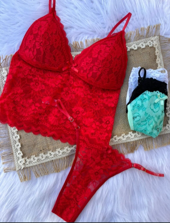 Conjunto de lencería de encaje rojo con tanga a juego, presentado sobre una superficie texturizada, y una pila de bragas de colores.
