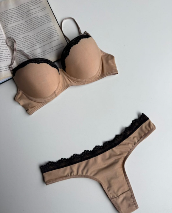 Sujetador rosa, tres tangas en rosa, tostado, negro y blanco; ribete de encaje. Libro abierto al fondo.