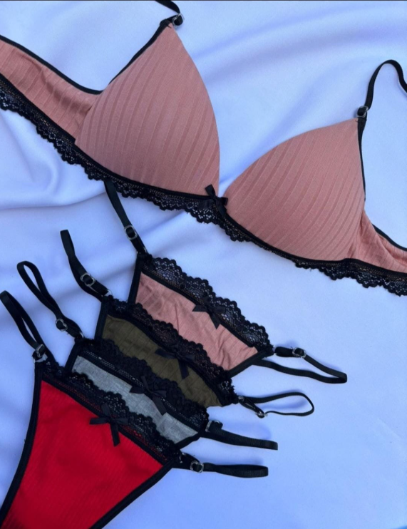 Mujer en lencería roja, con los brazos en alto, en una habitación.